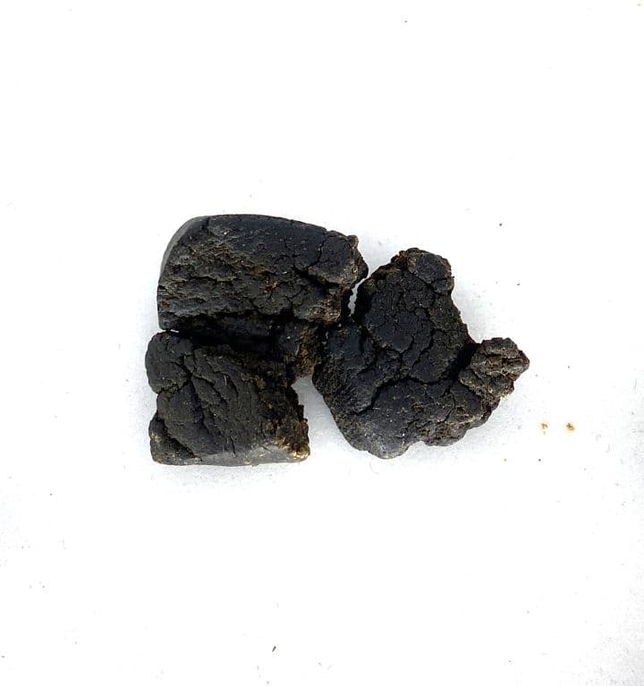 Dark black temple ball hash rolled into a smooth round sphere on a neutral background