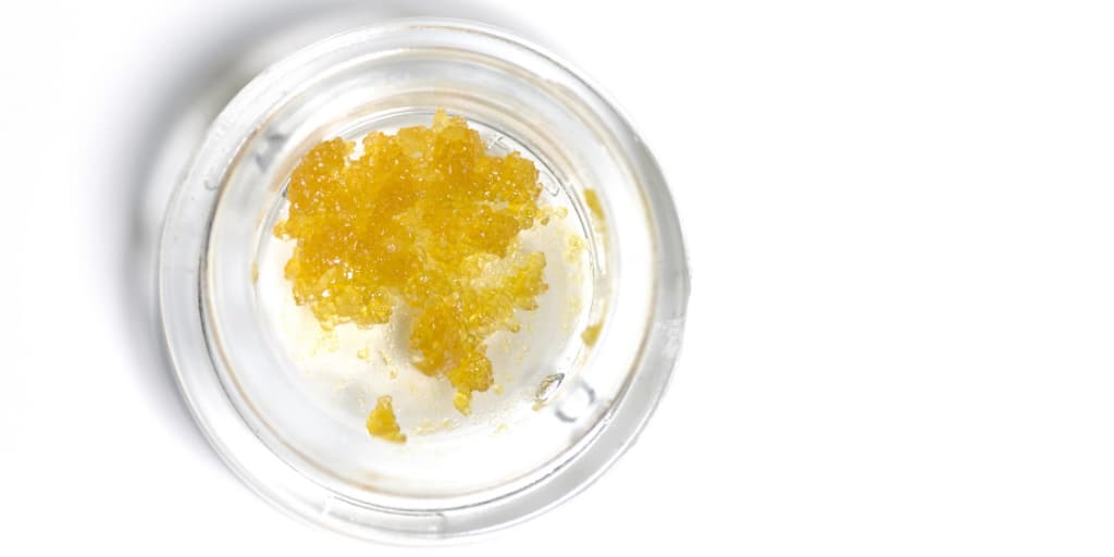 Golden live resin concentrate in a small glass jar, showcasing various cannabis strain options from Company 35