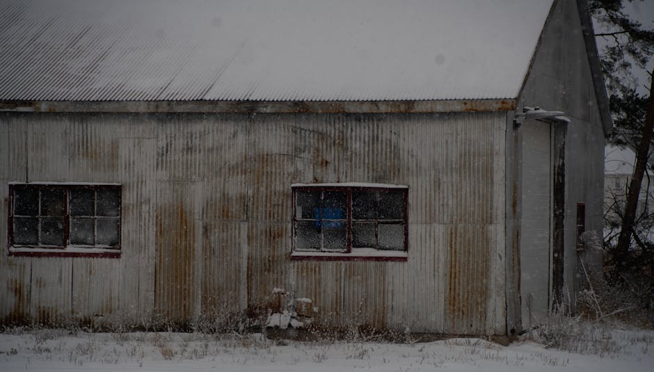 A rustic, abandoned structure covered in snow, capturing the essence of a harsh winter.
