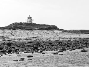 Black and white photo of a lighthouse on a rocky beach in Charlottetown, PE, Canada.