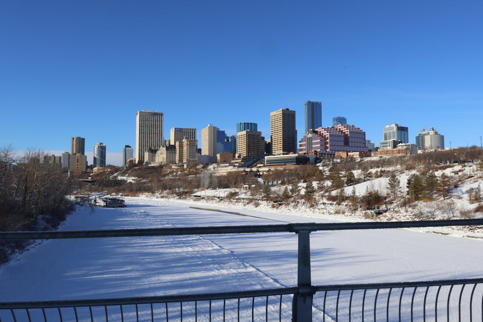 A scenic view of Edmonton's skyline during winter with a snow-covered river in the foreground.