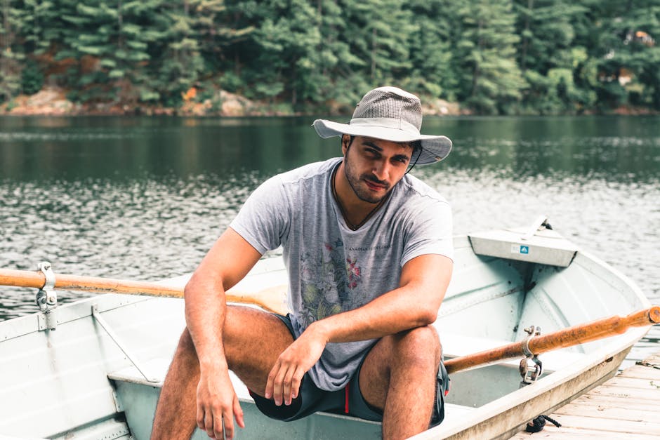 A man wearing a hat sits on a rowboat by a serene lake in Gatineau, Canada.