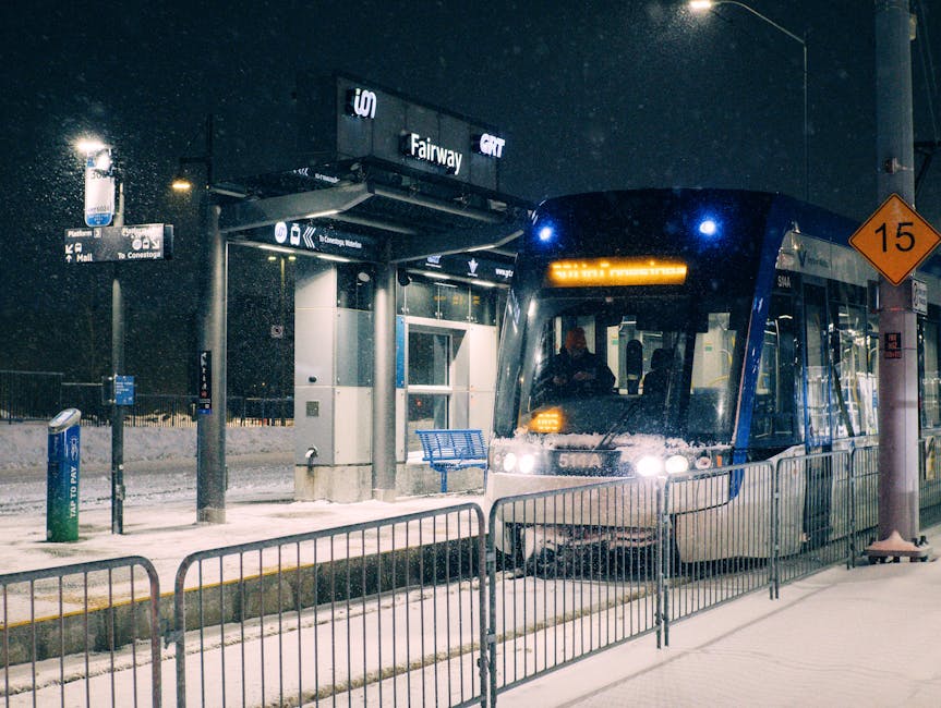 A snowy night at Fairway Station in Kitchener, Ontario with a light rail transit arriving.