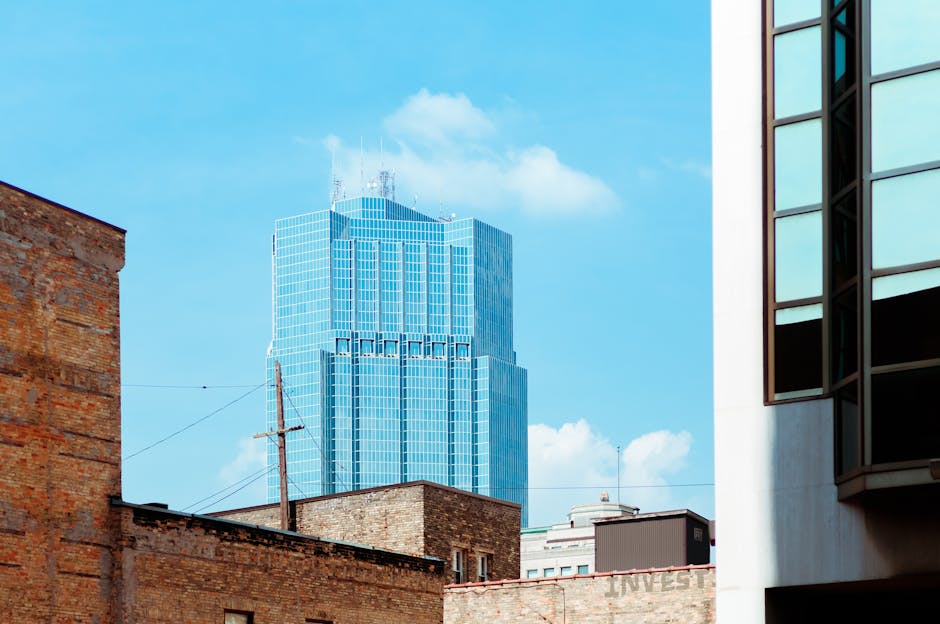 View of a modern skyscraper surrounded by brick buildings and blue sky in London, Ontario.