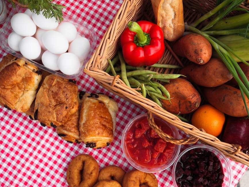 A vibrant picnic spread with fresh vegetables, pastries, and fruits on a gingham blanket.