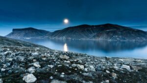Breathtaking moonlit view of Baffin Island's rugged landscape and tranquil waters.