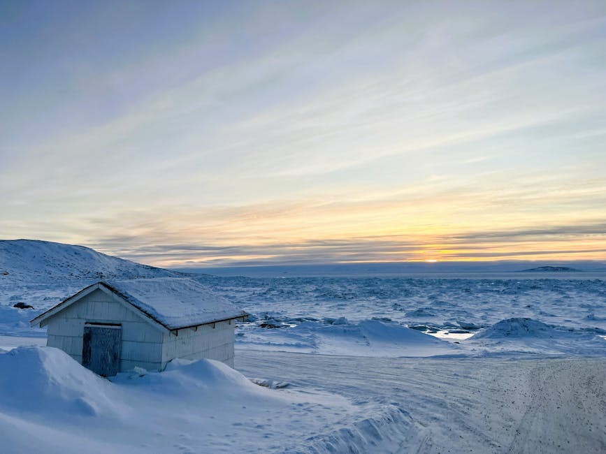 A serene snowy Arctic landscape in Apex, Canada with a house and frozen ocean at sunset.