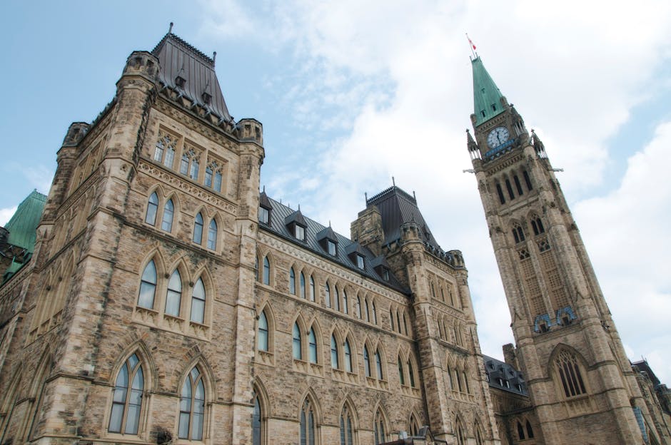 A view of the historical Parliament Hill building in Ottawa against a clear sky.
