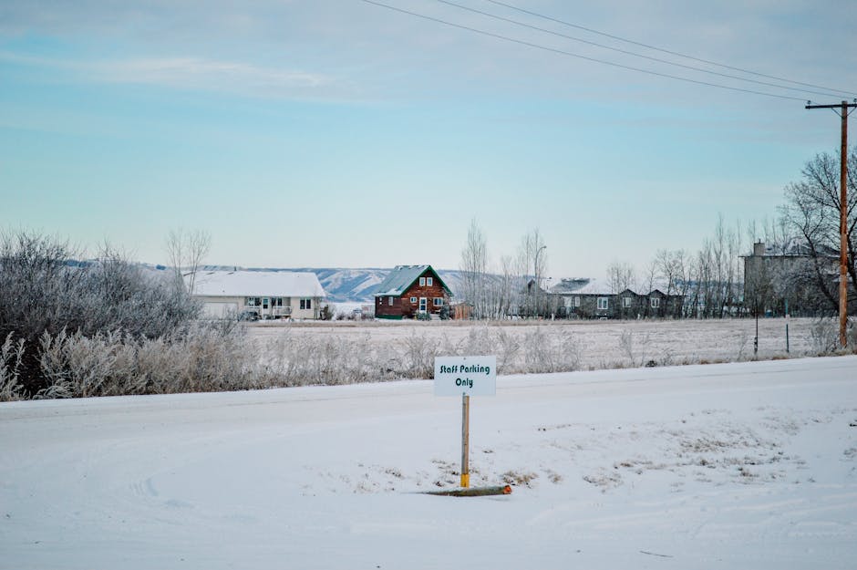 A serene winter landscape in Regina, Canada, featuring a rural village with snow-covered fields.