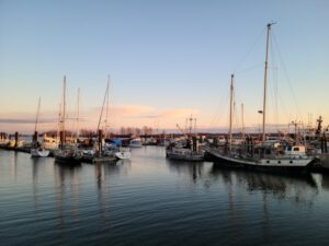 Explore a tranquil marina with boats and sailboats docked under a peaceful sunset sky in Richmond, BC, Canada.