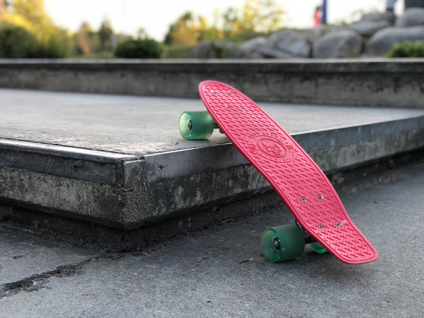 Vibrant pink skateboard resting on a concrete platform in an urban park setting during a summer day.