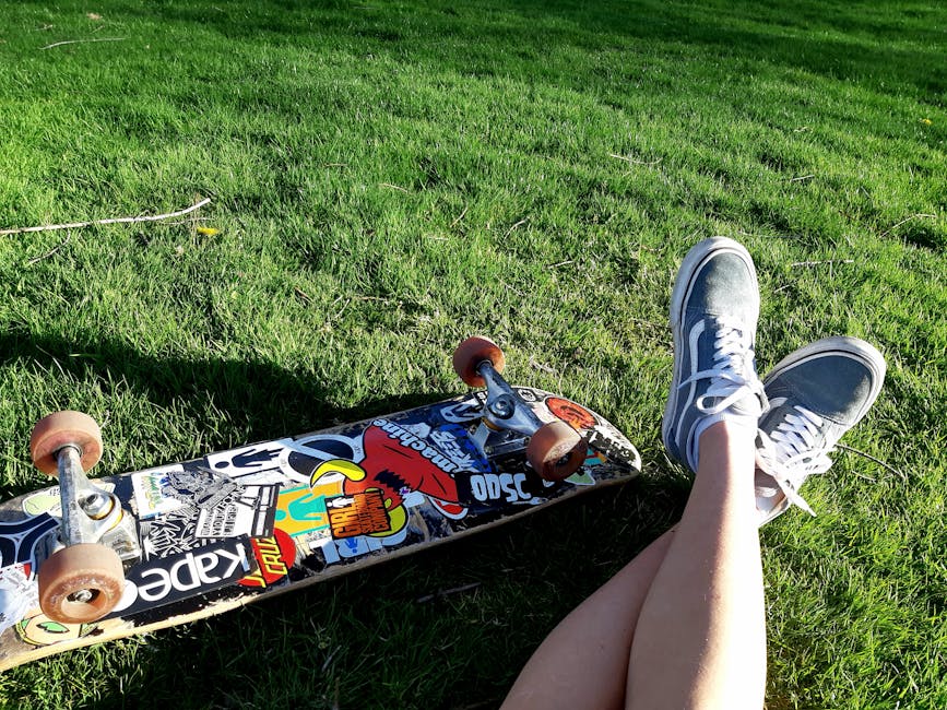 Person relaxing on green grass with skateboard nearby, showcasing leisure and outdoor lifestyle.